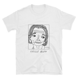 Puede incluir: Una camiseta blanca con un dibujo en blanco y negro de Lucille Bluth de la serie de televisión Arrested Development. El dibujo está en un marco cuadrado con el texto "Lucille Bluth" debajo.
