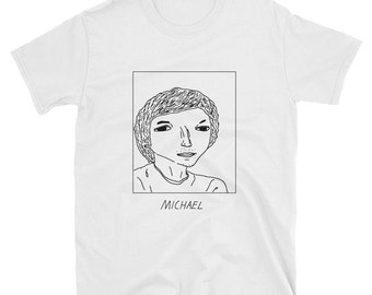 May include: A white t-shirt with a black and white line drawing of a person's face inside a square. The text "MICHAEL" is below the square.