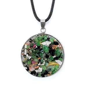 Könnte beinhalten: Eine runde Anhängerhalskette mit einem silberfarbenen Metallrahmen. Der Anhänger ist mit grünen, silbernen, schwarzen und rosa Steinen und Fragmenten gefüllt. Die Halskette hat eine schwarze Kordel.