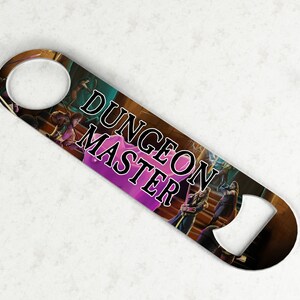 Könnte beinhalten: Ein silberner Flaschenöffner mit einem schwarzen und goldenen Design, das eine Fantasy-Szene und den Text "Dungeon Master" zeigt.