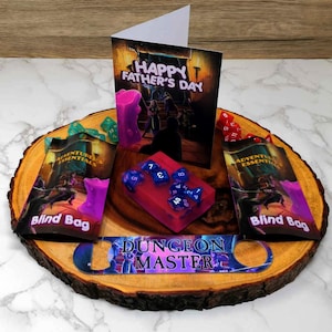 Può includere: Un vassoio di legno con un apribottiglie "Dungeon Master", due sacchetti ciechi "Adventure's Essentials", un biglietto con il testo "Happy Father's Day" e una saponetta rosa con dadi blu.