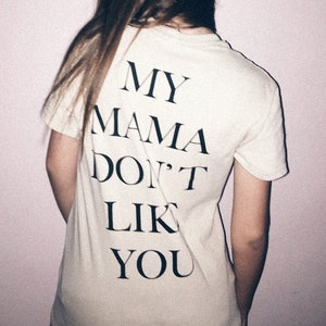 May include: A white t-shirt with black text that reads "MY MAMA DON'T LIKE YOU".