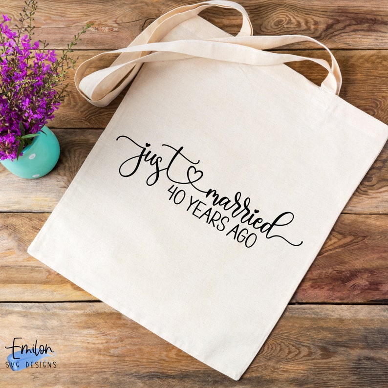 May include: A white canvas tote bag with black text that reads "just married 40 years ago" with a small heart symbol between the words "just" and "married".