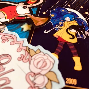 May include: A collection of colorful stickers featuring cartoon characters. One sticker depicts a girl in a yellow coat holding a black cat under a starry umbrella. Another shows a mouse in a red coat playing a horn. Other stickers include floral designs.