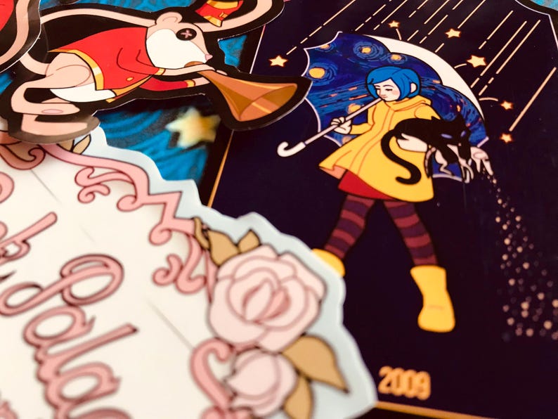 May include: A collection of colorful stickers featuring cartoon characters. One sticker depicts a girl in a yellow coat holding a black cat under a starry umbrella. Another shows a mouse in a red coat playing a horn. Other stickers include floral designs.