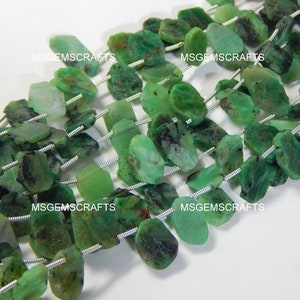 Könnte beinhalten: Eine Strähne grüner Edelsteinperlen mit rauer, unregelmäßiger Form. Die Perlen sind auf Silberdraht aufgefädelt.