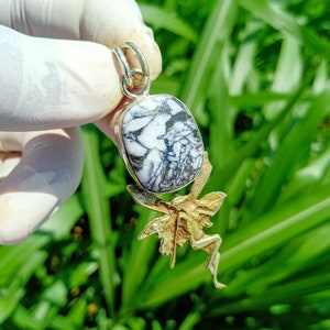 Peut inclure: Un pendentif en argent avec une pierre marbrée blanche et noire et un motif de fée dorée.