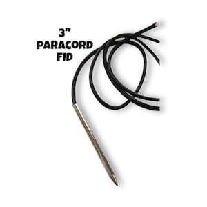 May include: A black paracord fid with a silver metal tip. The text "3" PARACORD FID" is printed in bold, black letters. The fid is approximately 3 inches long.