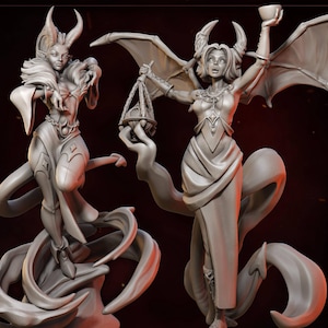 Puede incluir: Dos figuritas pintadas de gris de demonios femeninos con cuernos, alas y túnicas fluidas. Una sostiene una copa, la otra una balanza. Ambas están de pie sobre bases que giran.