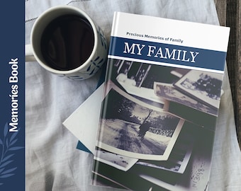 Może przedstawiać: Biała książka z niebieskim paskiem i tekstem "Precious Memories of Family MY FAMILY" na okładce. Książka leży na białym materiale tekstylnym z filiżanką kawy i białą kopertą.