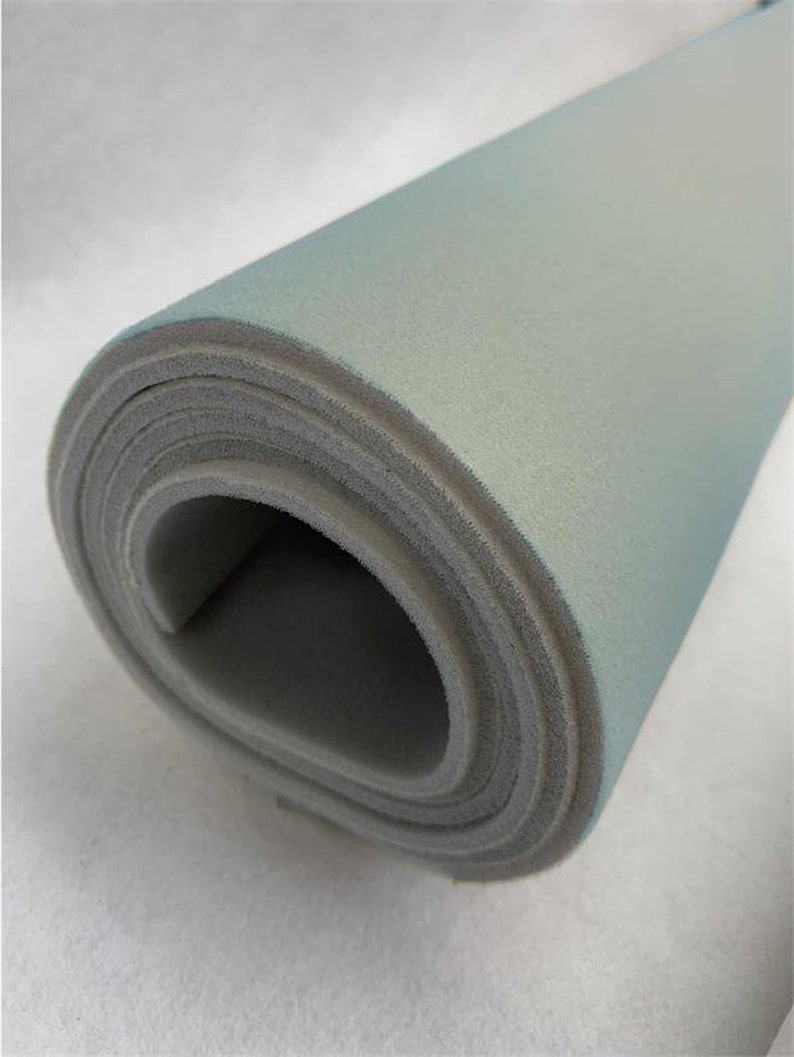 May include: A roll of light gray foam fabric. The fabric is rolled up tightly and the edges are visible.