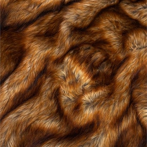 May include: Close-up of a faux fur fabric with a rich blend of brown, tan, and black fibers. The texture is dense and wavy, creating a luxurious appearance. The color variation adds depth and dimension to the material.