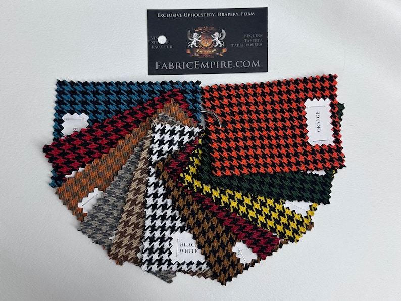 May include: A collection of fabric swatches in various houndstooth patterns, including black and white, red and black, orange and black, and teal and black. The swatches are arranged in a fan shape, with the label "ORANGE" visible on one of the swatches.
