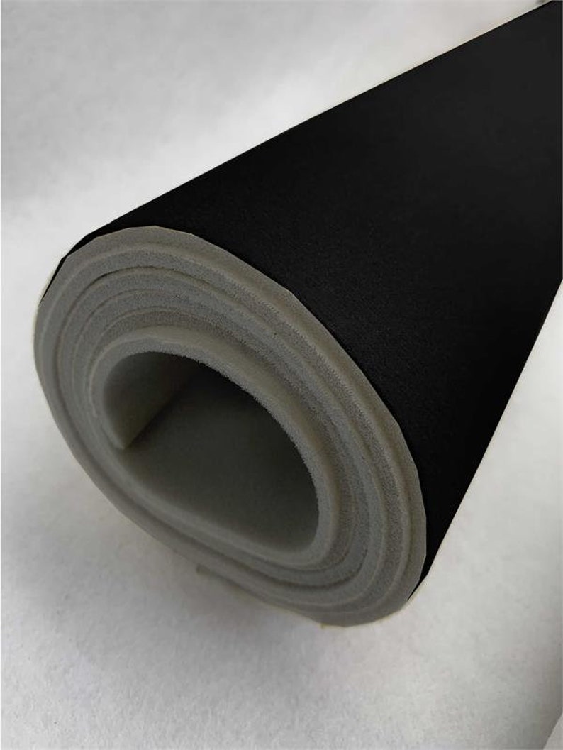 May include: A roll of black fabric with a gray foam backing. The fabric is rolled up tightly, showing the foam backing.