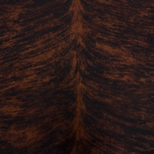 Puede incluir: Primer plano de un patrón de piel de vaca marrón y negro. La piel natural presenta una base marrón oscuro con vetas marrones claras y negras, creando una apariencia texturizada y orgánica. El patrón recuerda al pelaje animal.