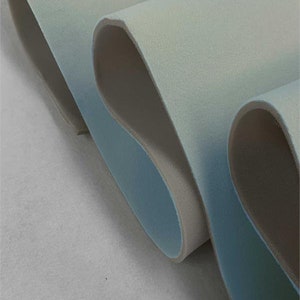 May include: Close-up of a folded piece of light blue and white fabric. The fabric has a soft, velvety texture.