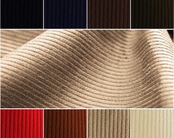 May include: A close-up of corduroy fabric in various colors, including beige, red, brown, cream, navy, black, and green. The fabric has a ribbed texture and is shown in a variety of folds and angles.