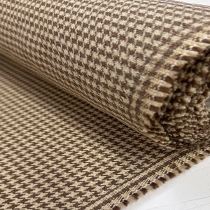 May include: A roll of brown and beige fabric with a houndstooth pattern.