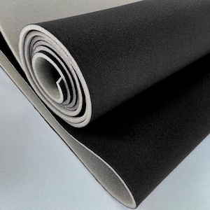 Puede incluir: Material de espuma negra enrollado con un interior y exterior gris claro. La espuma está enrollada firmemente, revelando los colores contrastantes del material. La textura de la espuma parece suave.