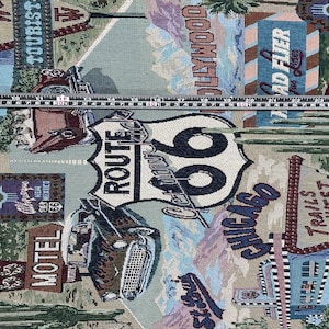 May include: A tapestry fabric with a vintage travel theme. The fabric features a Route 66 sign, a classic car, and various signs with text like "Motel", "Tourist Inn", "Hollywood", and "Trail's West".