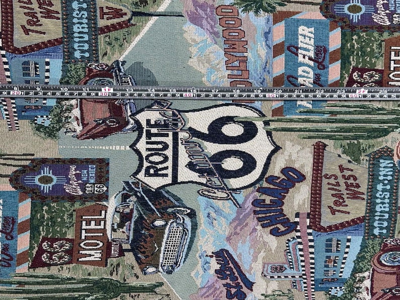 May include: A tapestry fabric with a vintage travel theme. The fabric features a Route 66 sign, a classic car, and various signs with text like "Motel", "Tourist Inn", "Hollywood", and "Trail's West".