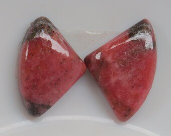 May include: Two pink and gray gemstone cabochons in a triangular shape.