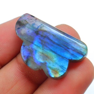 Puede incluir: Un cabujón de labradorita azul y verde con una forma única e irregular. La piedra preciosa tiene un brillo iridiscente.