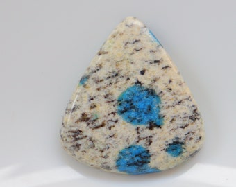 May include: A teardrop-shaped cabochon of blue and white speckled stone. The stone has a white background with blue spots.