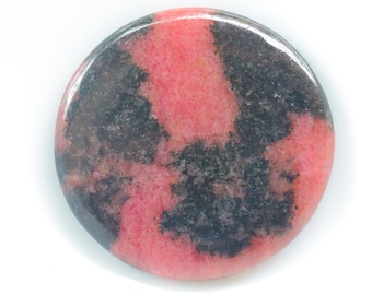 May include: A round, polished cabochon of pink and black rhodochrosite. The stone has a swirling pattern of pink and black.