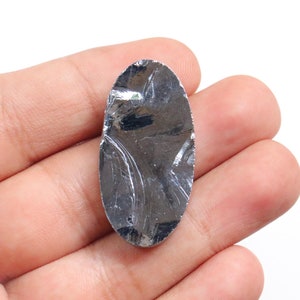 May include: A silver oval-shaped piece of raw, unpolished, natural, rough, or uncut,  mica, a mineral, with a reflective surface.