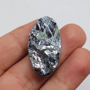 May include: A silver-colored, oval-shaped piece of raw, natural silicon. The silicon has a metallic sheen and a rough, textured surface.