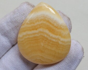 May include: A yellow and white banded agate cabochon in a teardrop shape.
