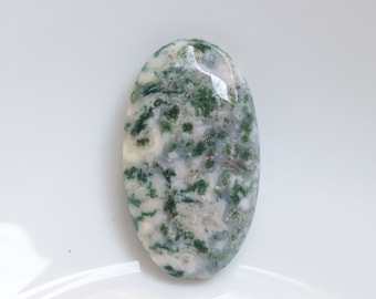 Op de afbeelding: Een groene en witte agaat cabochon met een gladde, ovale vorm. De steen heeft een draaiende patroon van groen en wit.
