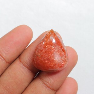 Pu&ograve; includere: Un cabochon di pietra di sole a forma di lacrima, di colore rosso-arancione e con una finitura scintillante e iridescente.