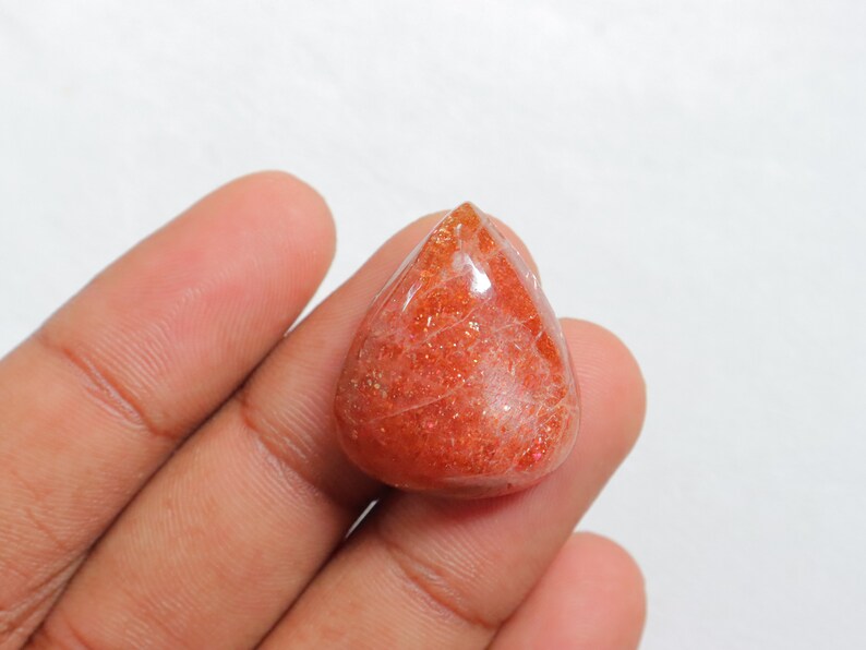 Pu&ograve; includere: Un cabochon di pietra di sole a forma di lacrima, di colore rosso-arancione e con una finitura scintillante e iridescente.