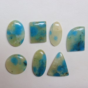 May include: Assortment of eight cabochon gemstones with a green and blue marbled pattern. The stones are various shapes, including oval, round, square, and triangular.