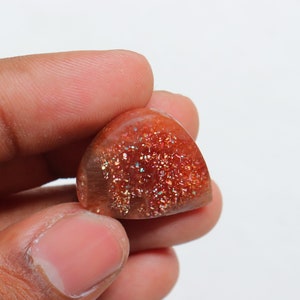 Pu&ograve; includere: Un cabochon di pietra di sole rosso, arancione e oro a forma di pera con una finitura scintillante e iridescente.