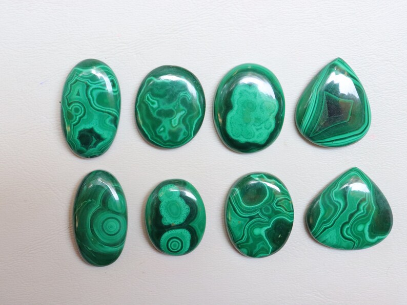 Puede incluir: Ocho cabujones de malaquita verde de diferentes formas y tama&ntilde;os. Los cabujones tienen un patr&oacute;n de remolino de verde y negro.