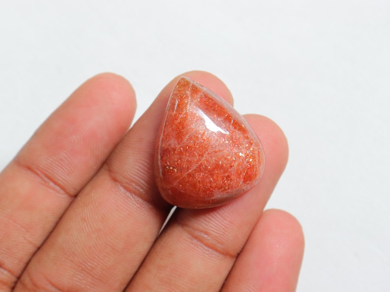 Pu&ograve; includere: Un cabochon di pietra di sole a forma di lacrima, di colore arancione e rosso traslucido. La pietra ha una qualit&agrave; scintillante e iridescente.