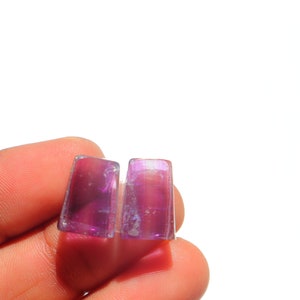 K&ouml;nnte beinhalten: Zwei rechteckige, violette und schillernde Glassteine.