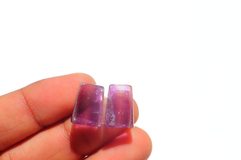 K&ouml;nnte beinhalten: Zwei rechteckige, violette und schillernde Glassteine.