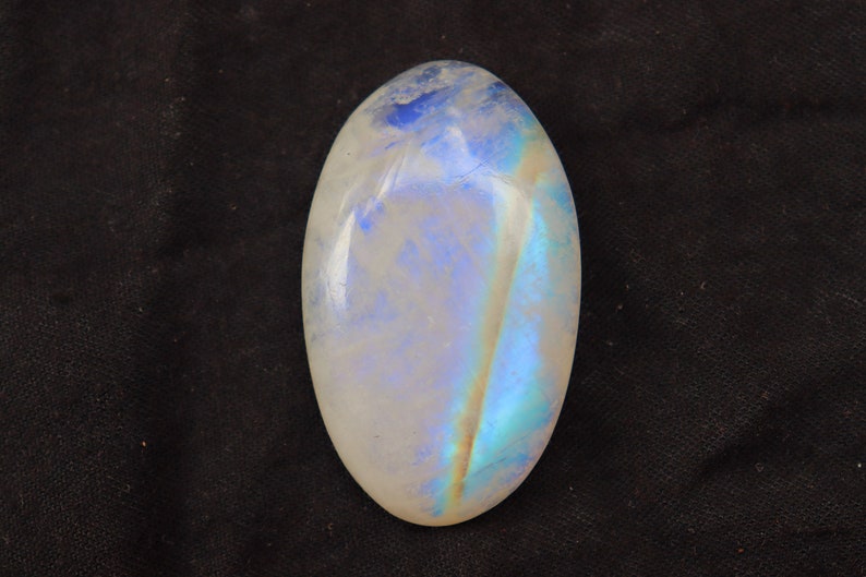 K&ouml;nnte beinhalten: Ein wei&szlig;er ovaler Mondstein-Cabochon mit schillernden blauen und gr&uuml;nen Blitzen.