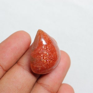 Pu&ograve; includere: Un cabochon di pietra di sole arancione a forma di lacrima con una finitura scintillante e iridescente.