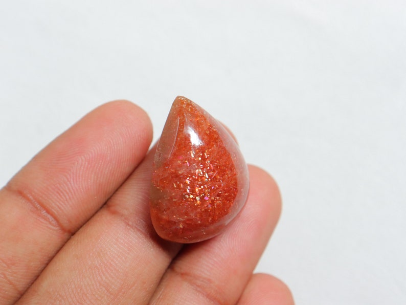 Pu&ograve; includere: Un cabochon di pietra di sole arancione a forma di lacrima con una finitura scintillante e iridescente.