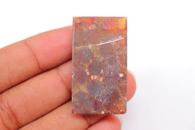 May include: A rectangular, polished, red, orange, and white agate gemstone with a unique, natural pattern.