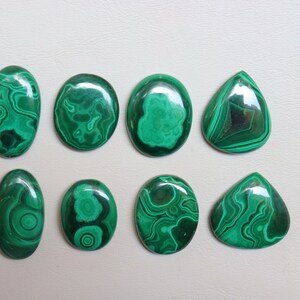 Puede incluir: Ocho cabujones de malaquita pulida en varias formas y tama&ntilde;os. Los cabujones son de color verde oscuro con intrincados patrones de vetas en espiral.