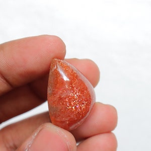 Pu&ograve; includere: Un cabochon di pietra di sole sfaccettato a forma di lacrima, di colore rosso-arancio translucido con una finitura scintillante e iridescente.