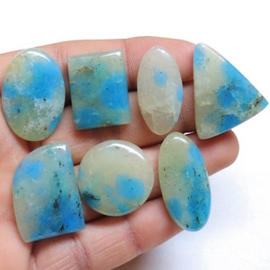 May include: Seven cabochon gemstones in various shapes and sizes, including oval, square, and triangular. The stones are a mix of white and blue with a mottled pattern.
