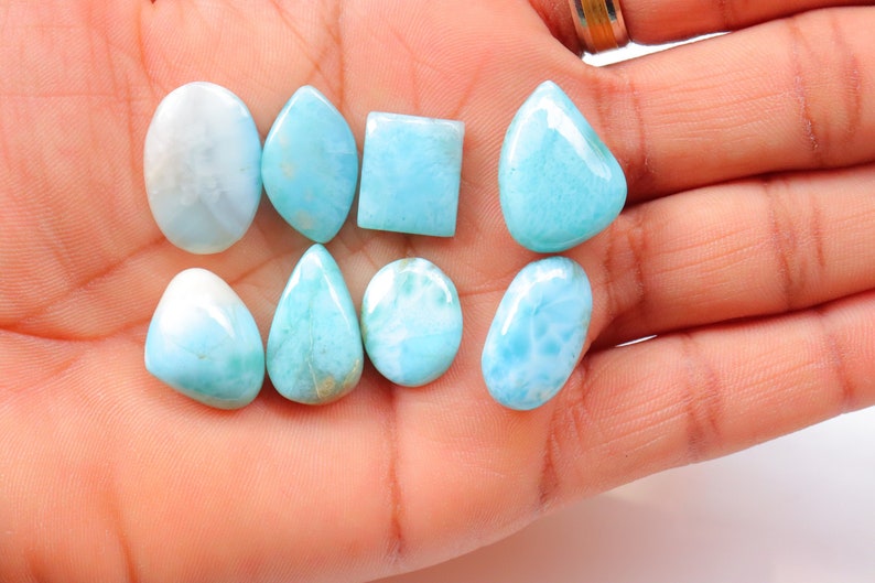 May include: A collection of ten blue and white cabochon gemstones, including oval, teardrop, square, and rectangular shapes.