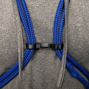 May include: A close-up of a gray hoodie with a black plastic clip holding two blue ropes.